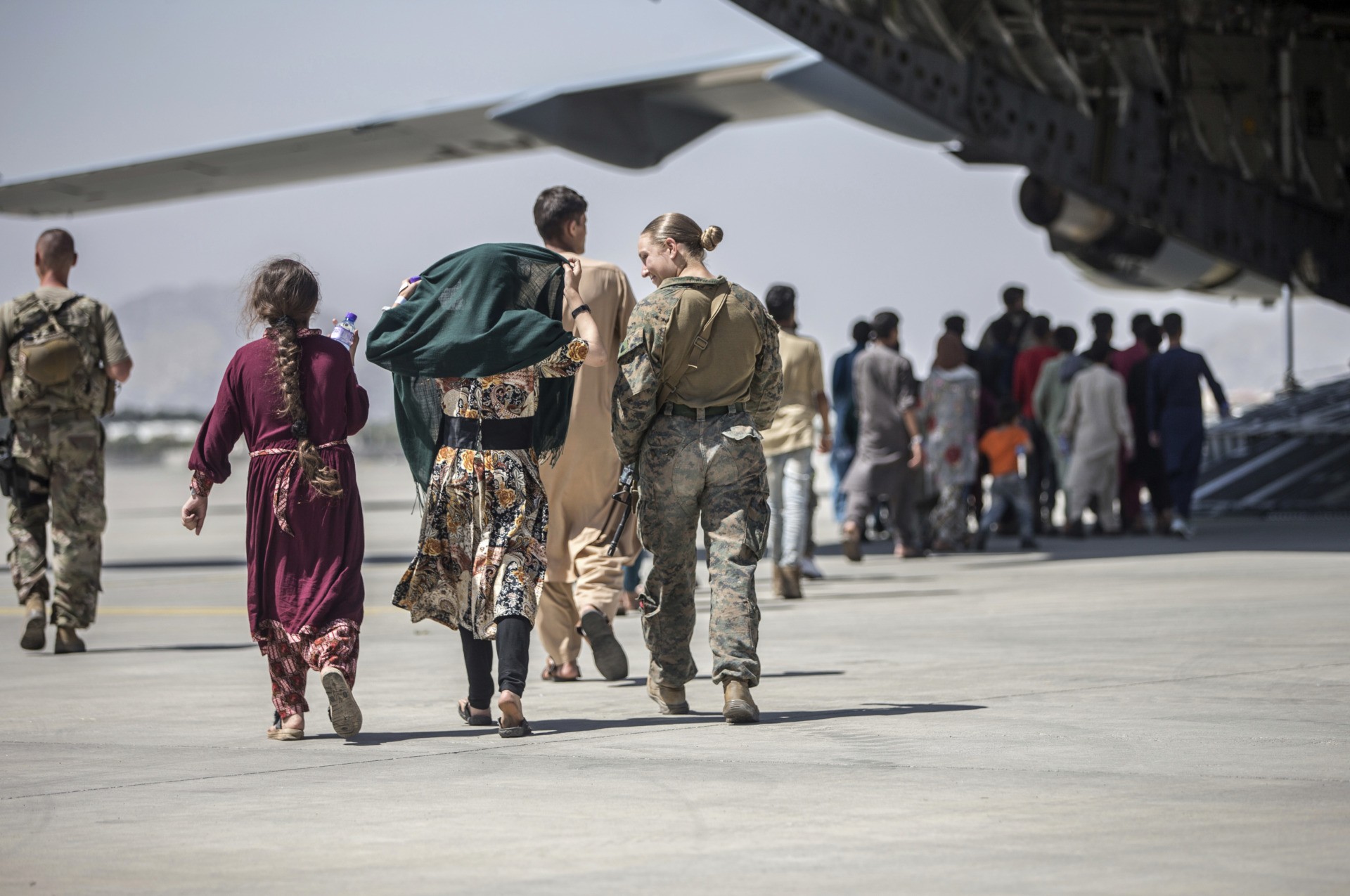 In this image provided by the U.S. Marine Corps, a Marine with the 24th Marine Expeditionary Unit walks with a family during ongoing evacuations at Hamid Karzai International Airport, Kabul, Afghanistan, Tuesday, Aug. 24, 2021. (Sgt. Samuel Ruiz/U.S. Marine Corps via AP)