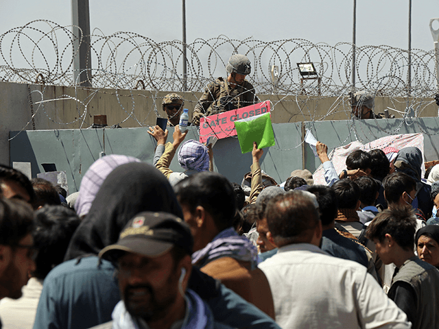A U.S. soldier holds a sign indicating a gate is closed as hundreds of people gather some holding documents, near an evacuation control checkpoint on the perimeter of the Hamid Karzai International Airport, in Kabul, Afghanistan, Thursday, Aug. 26, 2021. Western nations warned Thursday of a possible attack on Kabulâ€™s …