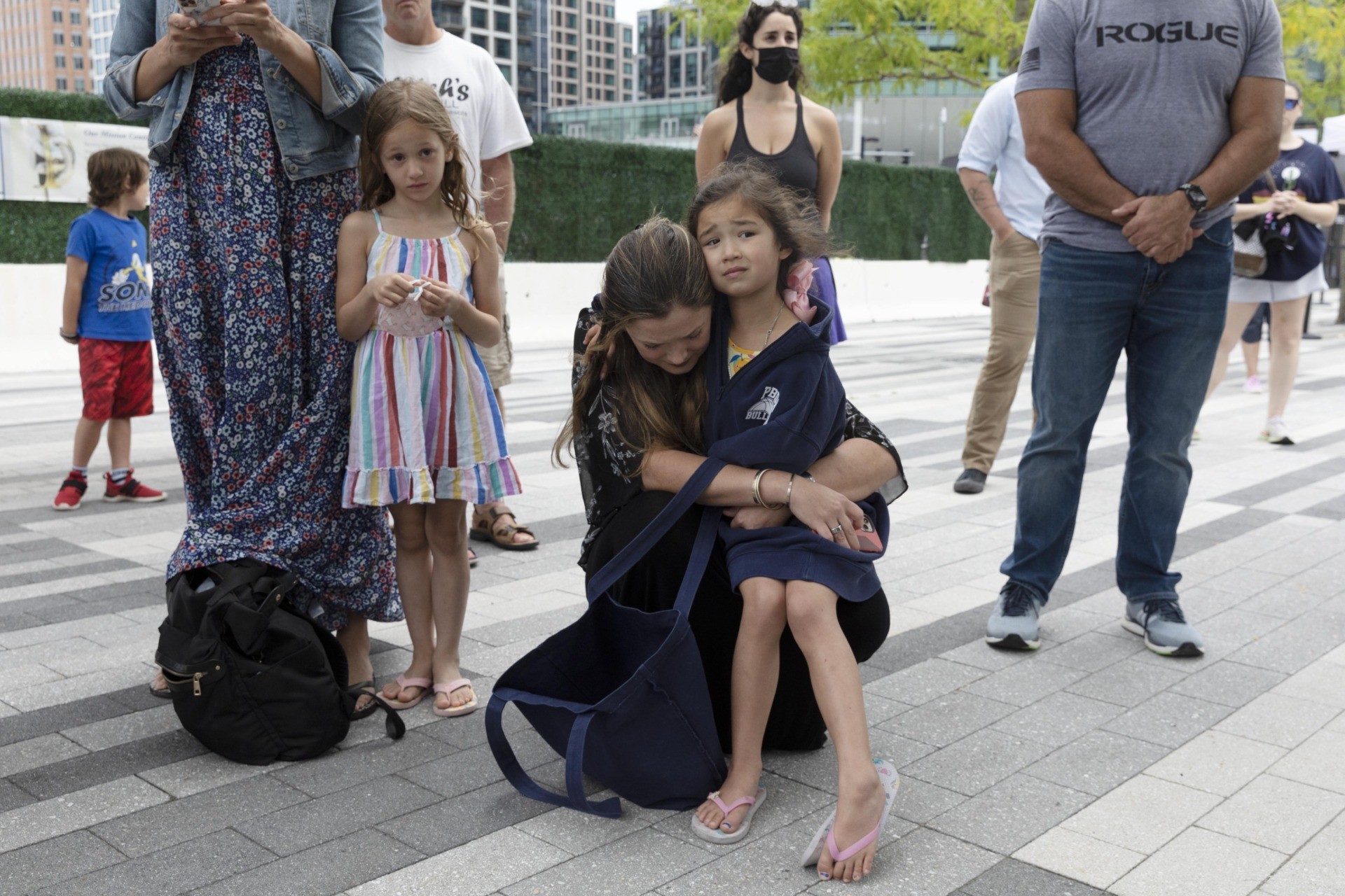 Ingrid Hammond, center, hugs her daughter Brigit during a ceremony at the Massachusetts Fallen Heroes Memorial, Saturday, Aug. 28, 2021, in Boston. People gathered at the memorial to honor the U.S. service members killed in a suicide bombing at the airport in Kabul, Afghanistan, including Marine Sgt. Johanny Rosario Pichardo from Lawrence, Mass. (AP Photo/Michael Dwyer)