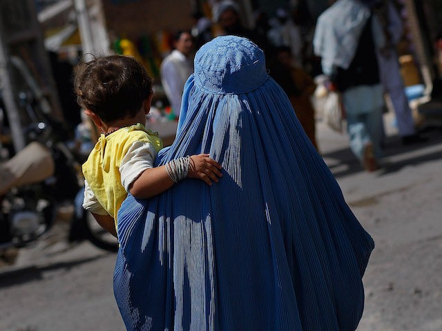 HERAT, HERAT PROVINCE - JUNE 26: An Afghan woman in a burqa carries a child June 26, 2010