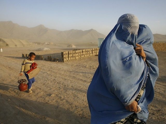 BARIKAB, AFGHANISTAN - AUGUST 5: An Afghan woman walks with her son against the strong winds on the barren, dusty plains where they are building a new home on land they have been given to settleAugust 5, 2007 in Barikab, Afghanistan. The new refugees along with hundreds of internally displaced …