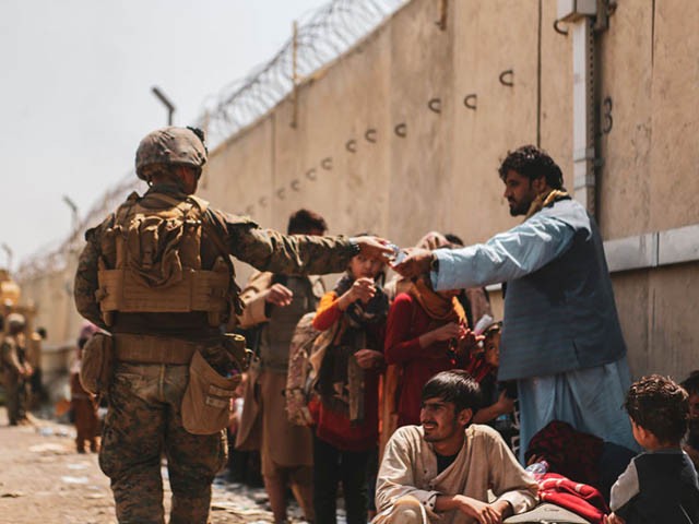 HAMID KARZAI INTERNATIONAL AIRPORT, AFGHANISTAN - AUGUST 22: This handout image shows A Marine with the 24th Marine Expeditionary unit (MEU) passes out water to evacuees during an evacuation at Hamid Karzai International Airport, Kabul, Afghanistan, Aug. 22. U.S. service members are assisting the Department of State with a Non-combatant Evacuation Operation (NEO) in Afghanistan. (Photo by Sgt. Isaiah Campbell / U.S. Marine Corps via Getty Images)