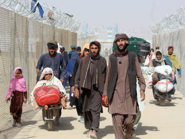 Afghan people walk inside a fenced corridor as they enter Pakistan at the Pakistan-Afghanistan border crossing point in Chaman on August 25, 2021 following the Taliban's stunning military takeover of Afghanistan. (Photo by - / AFP) (Photo by -/AFP via Getty Images)