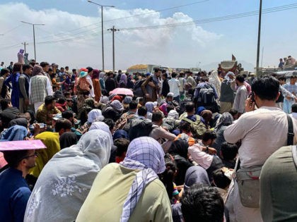 Afghan people gather along a road as they wait to board a U S military aircraft to leave t