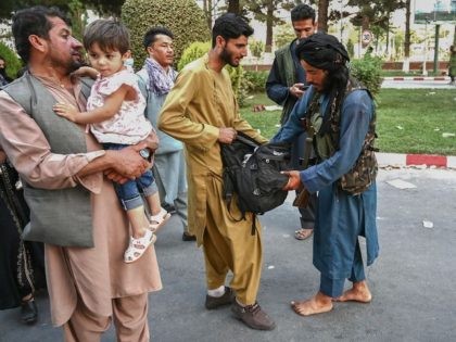 A Taliban fighter (R) searches the bags of people coming out of the Kabul airport in Kabul on August 16, 2021, after a stunningly swift end to Afghanistan's 20-year war, as thousands of people mobbed the city's airport trying to flee the group's feared hardline brand of Islamist rule. (Photo …