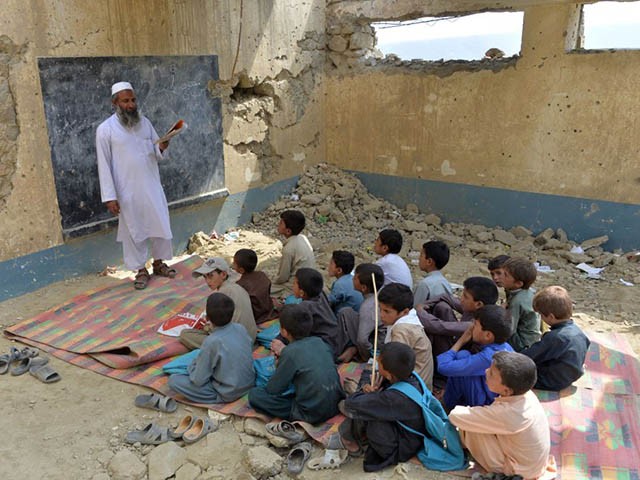 In this photo taken on July 25, 2019, Afghan schoolchildren study at the destroyed Papen High School in Deh Bala district of Nangarhar province. - The US and the Taliban say they are making progress in ongoing peace talks, but little has changed for ordinary Afghans, and recent attacks show how children are as vulnerable as ever in the grinding conflict. (Photo by NOORULLAH SHIRZADA / AFP) / TO GO WITH Afghanistan-conflict-children-education,FOCUS by Thomas Watkins and Noorullah Shirzada (Photo credit should read NOORULLAH SHIRZADA/AFP via Getty Images)