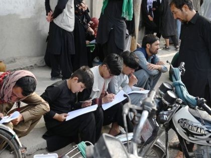 Afghan people fill up their details on a sheet of paper to register their name in order to leave the country in front of the British and Canadian embassy in Kabul on August 19, 2021, after the Taliban's military takeover of Afghanistan. (Wakil Kohsar/AFP via Getty Images)