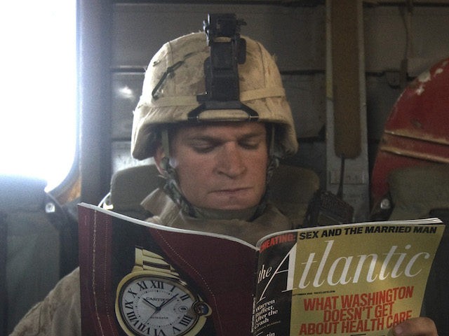 A US Marine reads a copy of Atlantic magazine with a cover photo of US President Barack Ob
