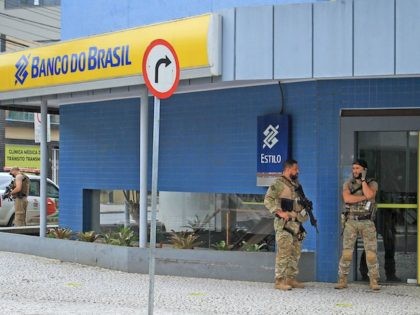 Police officers stand guard outside the bank which robbers struck just after midnight, in Criciuma, Brazil, on December 1, 2020. - A group of 30 heavily armed criminals entered a bank in Criciuma, Santa Catarina State, southern Brazil, taking hostages, blocking roads and exchanging gun fire with police for about …