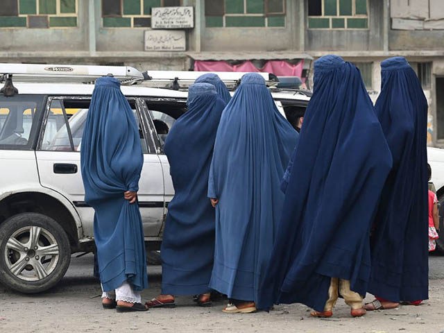 Women wearing a burqa wait to board into a local taxi in Kabul on July 31, 2021. (Photo by