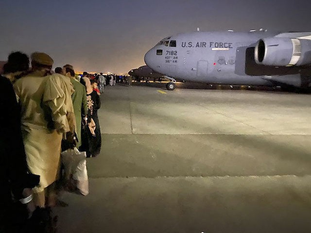 Afghan people queue up and board a U S military aircraft to leave Afghanistan, at the mili