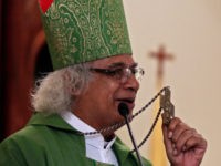 Cardinal Leopoldo Brenes holds up his cross as he gives his homily during Mass at the Jesus of Divine Mercy church in Managua, Nicaragua, Sunday, July 22, 2018. Nicaraguan President Daniel Ortega has attacked Nicaragua's Roman Catholic Church as allies of "coup mongers." (AP Photo/Arnulfo Franco)