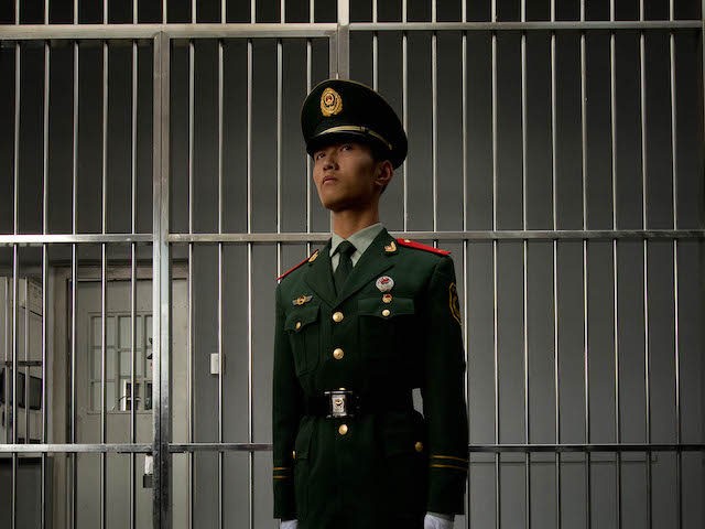 A paramilitary guard stands before the bars of a main gate to the No.1 Detention Center during a government guided tour in Beijing on October 25, 2012. The rare visit to the facility, which has capacity for 1,000 inmates, was opened to the foreign media as Beijing prepares for the …