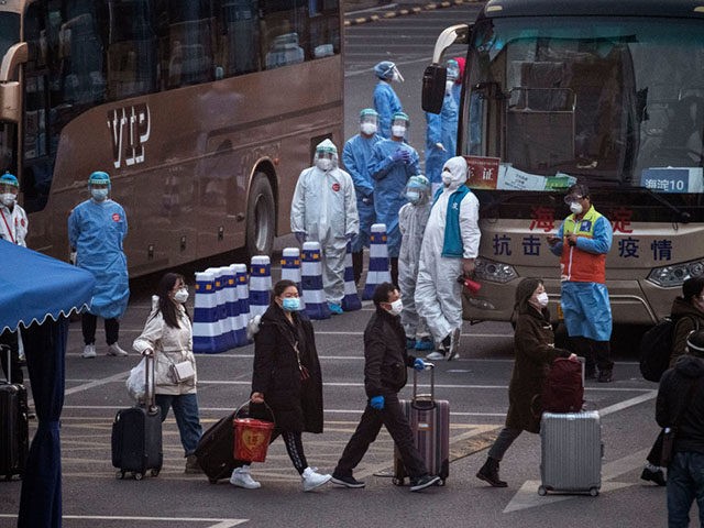 BEIJING, CHINA - APRIL 10: Chinese workers and health officials wear protective suits as they watch travellers from Hubei province, including Wuhan, as they gather to take buses while being processed and taken to do 14 days of quarantine, after arriving by train on April 10, 2020 in Beijing, China. …