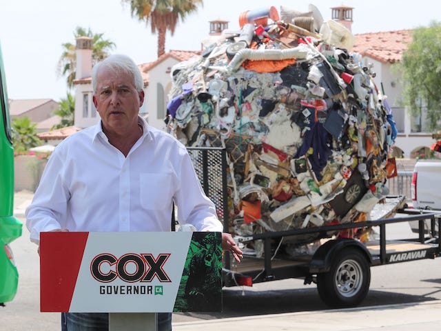 California Repubican gubernatorial candidate John Cox speaks in front of a large ball of trash meant to bring attention to the homelessness situation during a campaign stop in Palm Springs, July 13, 2021. Cox and trash ball