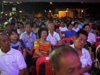 In this Wednesday Aug. 21, 2013 photo, residents join "dead souls" to watch a concert of song and dance during the "Hungry Ghost Festival" celebrated in Singapore. During the month of August, Taoists and Buddhists believe that the "Gates of Hell" are opened and the souls of the dead are …