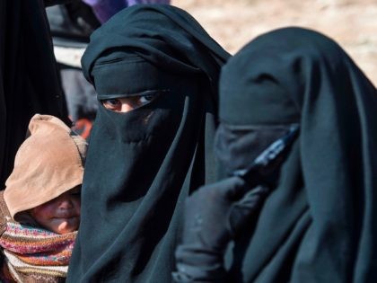 Fully veiled women fleeing from the Baghouz area in the eastern Syrian province of Deir Ezzor queue up in a field on February 12, 2019 during an operation by the US-backed Syrian Democratic Forces (SDF) to expel hundreds of Islamic State group (IS) jihadists from the region. - The ferocious …
