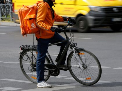 An employee of Lieferando food delivery company stops at a traffic light at a roundabout as a DHL delivery van drives past in Berlin's Kreuzberg district on April 15, 2020 amid the novel coronavirus COVID-19 pandemic. (Photo by David GANNON / AFP) (Photo by DAVID GANNON/AFP via Getty Images)