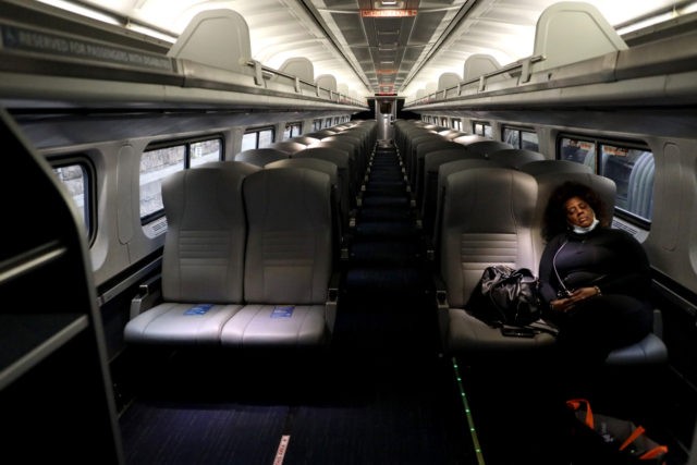BALTIMORE, MARYLAND - APRIL 09: A lone passenger sleeps in an otherwise empty Amtrak car a