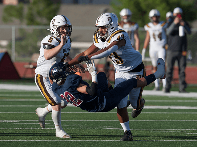 Dominic Martucci #22 of the Herriman Mustangs is taken down by Ephraim Fiso #43 and Caden