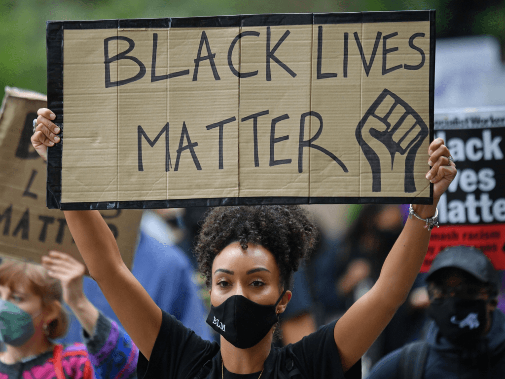 People hold up placards in support of the Black Lives Matter movement as they take part in the inaugural Million People March march from Notting Hill to Hyde Park in London on August 30, 2020, to put pressure on the UK Government into changing the "UK's institutional and systemic racism". - The march is organised by The Million People Movement, and takes place on the bank holiday weekend usually associated with the Notting Hill Carnival, this year cancelled due to the coronavirus covid-19 pandemic. (Photo by JUSTIN TALLIS / AFP) (Photo by JUSTIN TALLIS/AFP via Getty Images)