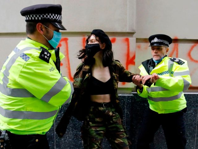 An activist is arrested by police officers at a demonstration against the HS2 hi-speed rail line where protesters sprayed fake blood and graffiti outside the Department for Transport, as part of protests by the Extinction Rebellion climate change group in central London on September 4, 2020 on the fourth day …
