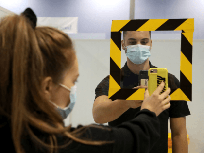 Kitty Ritchie poses for a photograph whilst having a QR code on her mobile phone scanned, whilst demonstrating the processes of having a coronavirus test, during a photocall at the new walk-through COVID-19 testing centre at Glasgow Caledonian University's ARC sports centre, in Glasgow on September 18, 2020. - Millions …