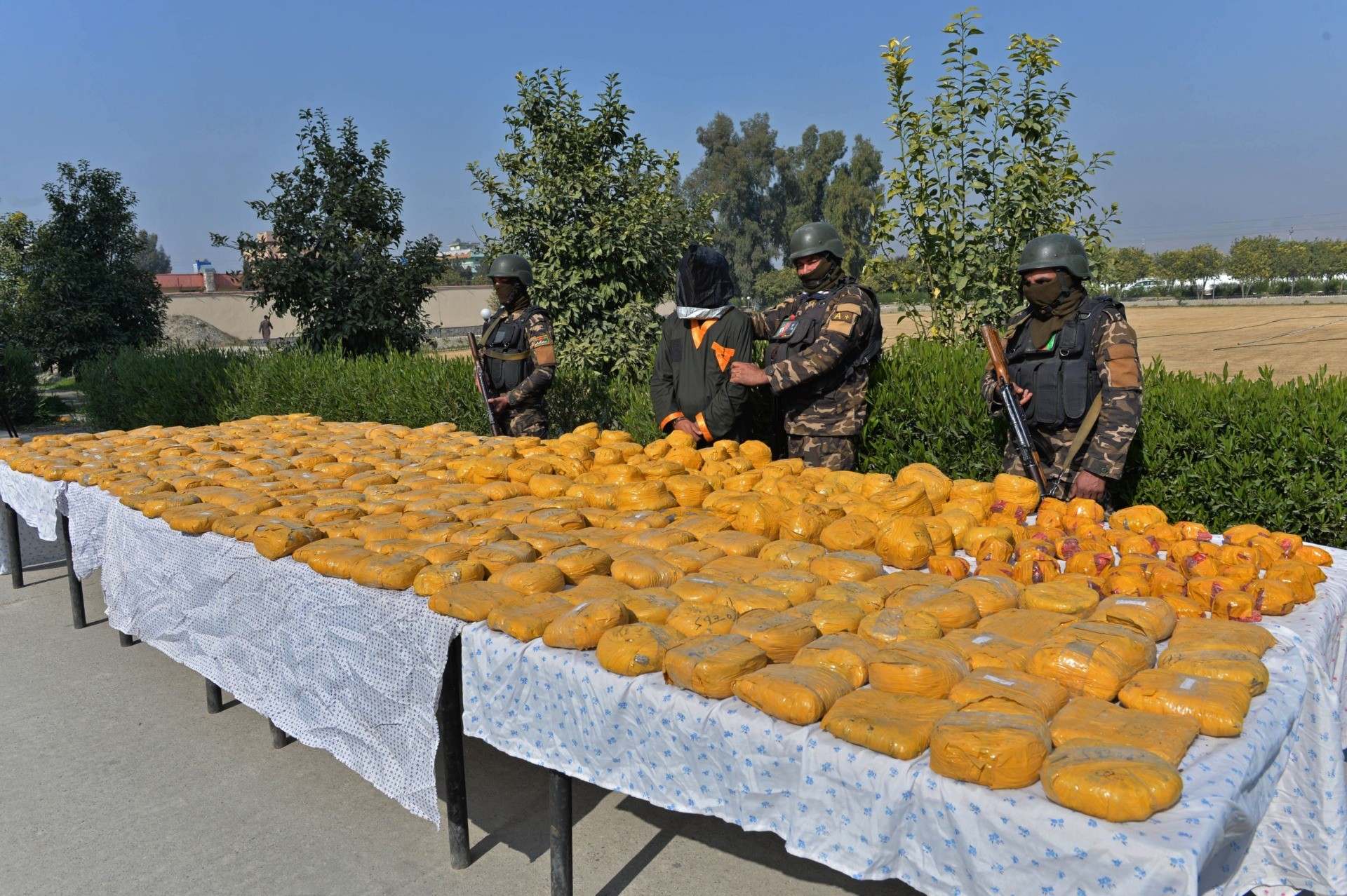 National Directorate of Security (NDS) forces stand guard along with a detained suspect (C) after bags containing Opium and Hashish were seized in an operation during a press conference at NDS headquarters in Jalalabad on February 4, 2021. (Photo by NOORULLAH SHIRZADA / AFP) (Photo by NOORULLAH SHIRZADA/AFP via Getty Images)