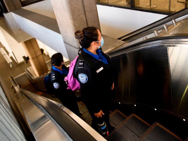 Transportation Security Administration (TSA) agents wear face masks as they ride an escala