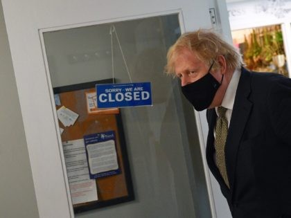 TRURO, ENGLAND - APRIL 07: British Prime Minister Boris Johnson walks past a sign reading 'We are Closed' during a visit to Lemonheads Barber shop inside Lemon Street Market on April 7, 2021 in Truro, England. The Prime Minister visited businesses in Cornwall to see how they are preparing to …