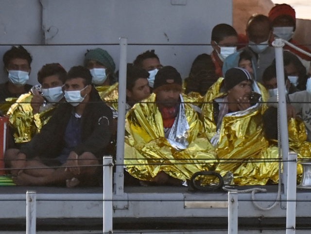 Migrants warmed by emergency blankets arrive on a boat of the Italian Guardia Di Finanza l