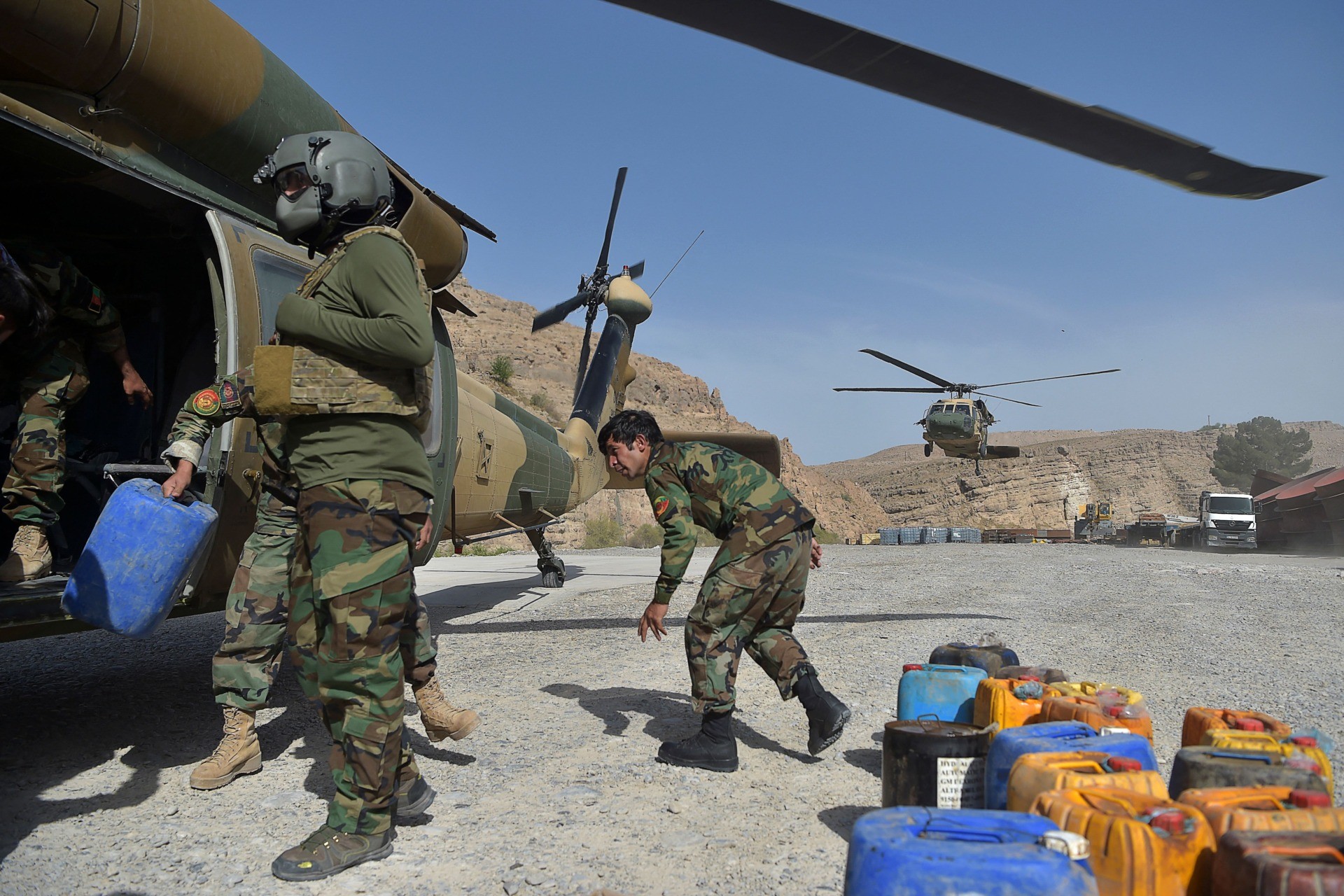 In this photograph taken on March 25, 2021, Afghan National Army (ANA) soldiers unload food items and petrol oil from an Afghan Air Force Black Hawk helicopter at the hydroelectric Kajaki Dam in Kajaki, northeast of Helmand Province. - In the heart of territory under siege from the Taliban, one of Afghanistan's most important hydroelectric dams is at the centre of a power struggle that symbolises the battle between the government and insurgents. - TO GO WITH Afghanistan-environment-dam-Taliban,FOCUS by Elise BLANCHARD (Photo by WAKIL KOHSAR / AFP) / TO GO WITH Afghanistan-environment-dam-Taliban,FOCUS by Elise BLANCHARD (Photo by WAKIL KOHSAR/AFP via Getty Images)