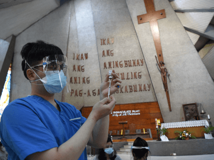 A health worker (L) prepares to inoculate residents with a dose of the AstraZeneca/Oxford's Covid-19 coronavirus vaccine inside a Catholic church turned into a vaccination centre in Manila on May 21, 2021. (Photo by TED ALJIBE / AFP) (Photo by TED ALJIBE/AFP via Getty Images)