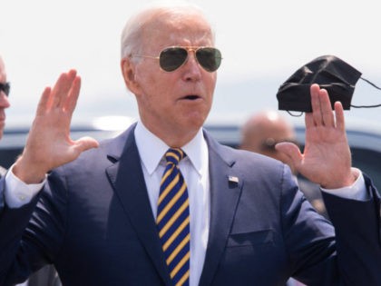 US President Joe Biden answers a question from the press as he holds a mask upon arrival