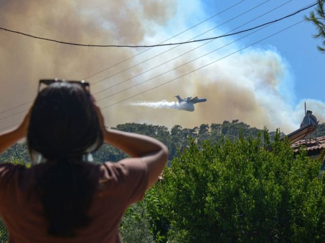 A firefighting aircraft drops water to extinguish a massive forest fire which engulfed a M