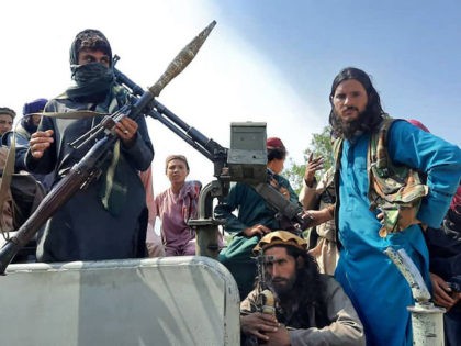 TOPSHOT - Taliban fighters sit over a vehicle on a street in Laghman province on August 15