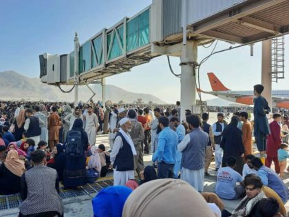 TOPSHOT - Afghans crowd at the tarmac of the Kabul airport on August 16, 2021, to flee the