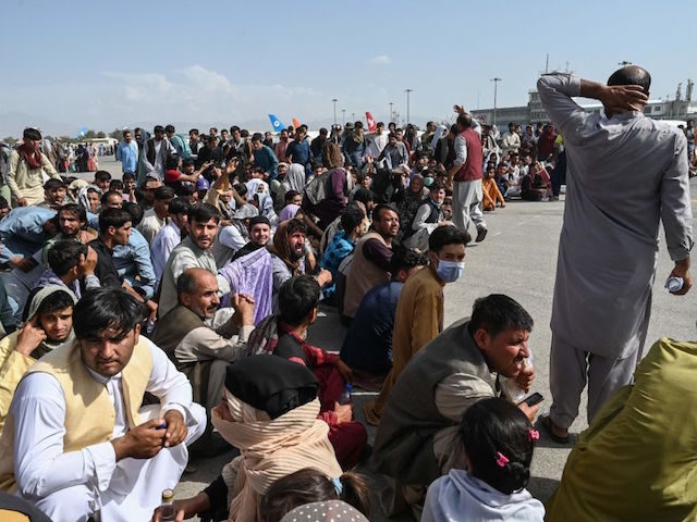 TOPSHOT - Afghan passengers sit as they wait to leave the Kabul airport in Kabul on August 16, 2021, after a stunningly swift end to Afghanistan's 20-year war, as thousands of people mobbed the city's airport trying to flee the group's feared hardline brand of Islamist rule. (Photo by Wakil …