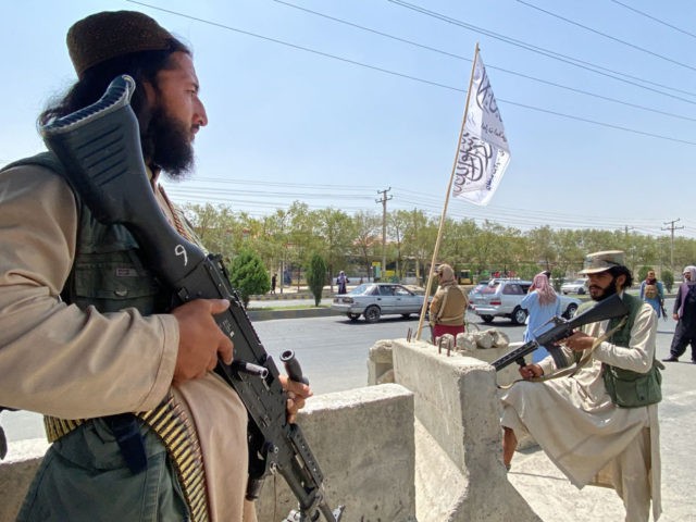 Taliban fighters stand guard at an entrance gate outside the Interior Ministry in Kabul on