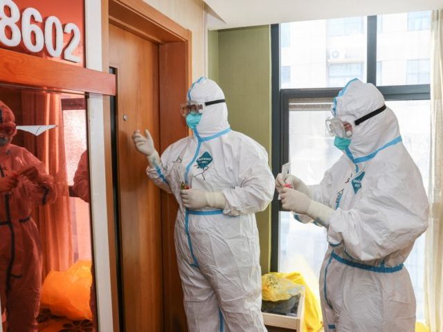 Medical staff members wearing personal protective equipment (PPE) against the spread of Covid-19 coronavirus knock on a door as they collect samples to be tested for the virus at a quarantine hotel in Lianyungang in China's eastern Jiangsu province on August 19, 2021. - China OUT (Photo by STR / …