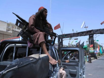 A Taliban fighter stands guard atop a vehicle near the site of an Ashura procession which is held to mark the death of Imam Hussein, the grandson of Prophet Mohammad, along a road in Herat on August 19, 2021, amid the Taliban's military takeover of Afghanistan. (Photo by AREF KARIMI …