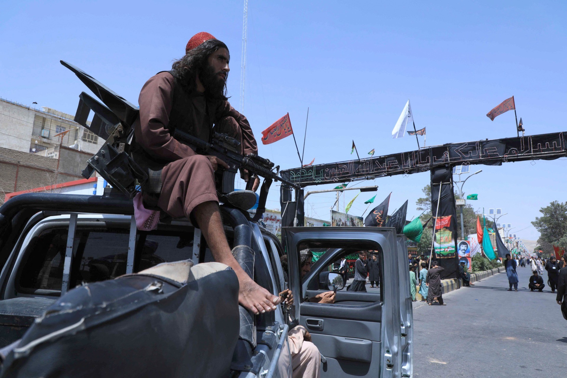 A Taliban fighter stands guard atop a vehicle near the site of an Ashura procession which is held to mark the death of Imam Hussein, the grandson of Prophet Mohammad, along a road in Herat on August 19, 2021, amid the Taliban's military takeover of Afghanistan. (Photo by AREF KARIMI / AFP) (Photo by AREF KARIMI/AFP via Getty Images)