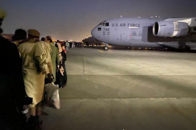 Afghan people queue up and board a U S military aircraft to leave Afghanistan, at the mili