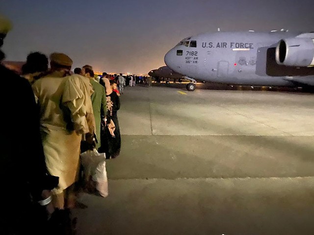 Afghan people queue up and board a U S military aircraft to leave Afghanistan, at the military airport in Kabul on August 19, 2021 after Taliban's military takeover of Afghanistan. (Photo by Shakib RAHMANI / AFP) (Photo by SHAKIB RAHMANI/AFP via Getty Images)
