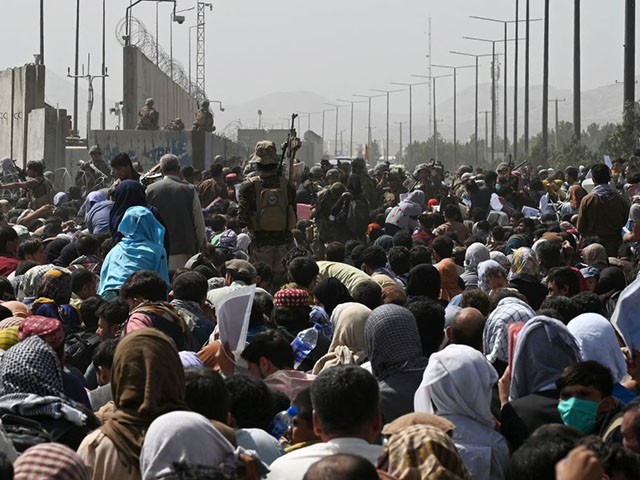 TOPSHOT - Afghans gather on a roadside near the military part of the airport in Kabul on August 20, 2021, hoping to flee from the country after the Taliban's military takeover of Afghanistan. (Photo by Wakil KOHSAR / AFP) (Photo by WAKIL KOHSAR/AFP via Getty Images)