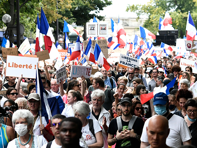Protesters wave French flags and hold banners reading "freedom" as they march during a national day of protest against the compulsory Covid-19 vaccination for certain workers and the mandatory use of the health pass called for by the French government in Paris on August 21, 2021. - Protesters took to …