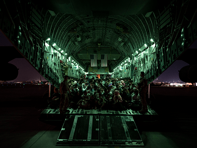 In this handout provided by the U.S. Air Force, an air crew assigned to the 816th Expeditionary Airlift Squadron assists evacuees aboard a C-17 Globemaster III aircraft in support of the Afghanistan evacuation at Hamid Karzai International Airport on August 21, 2021 in Kabul, Afghanistan. (Photo by Taylor Crul/U.S. Air Force via Getty Images)