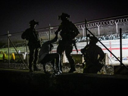 In this picture taken in the late hours on August 22, 2021 British and Canadian soldiers help an Afghan climb up on the wall of a canal as he with others wait near the foreign military-controlled part of the airport in Kabul, hoping to flee the country following the Taliban's …