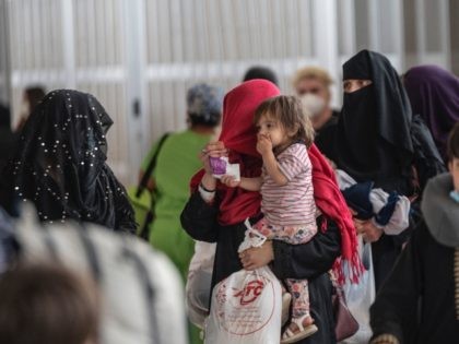 Refugees from Afghanistan are escorted to a waiting bus after arriving and being processed