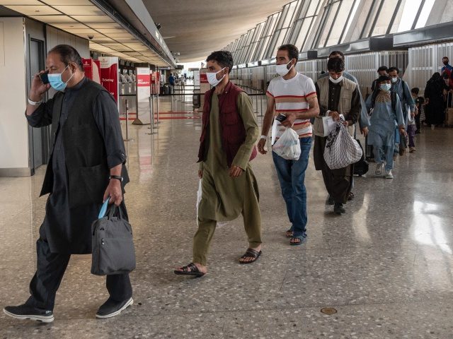 Refugees from Afghanistan are escorted to a waiting bus after arriving and being processed at Dulles International Airport in Dulles, Virginia on August 23, 2021. - Around 16,000 people were evacuated over the past 24 hours from Afghanistan through the Kabul airport, the Pentagon said on August 23, 2021, as …